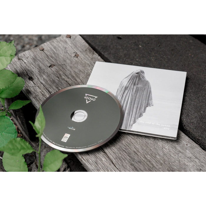 A CD by The End Of The Ocean sits on a weathered wooden surface next to its case, which shows a monochrome figure draped in cloth, suggesting redemption. Green leaves appear in the imageβs corner.