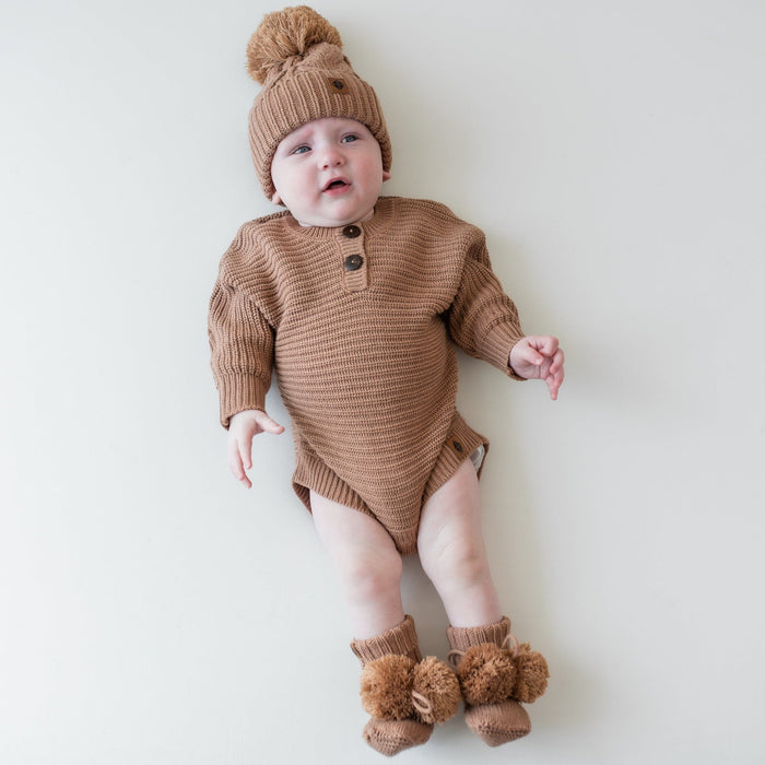 Infant wearing the Chunky Cable Knit Beanie in Latte paired with matching chunky knit romper and knit booties