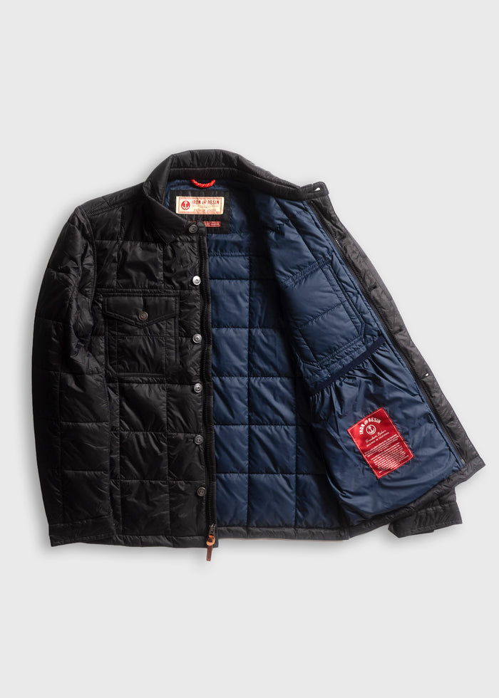 Black quilted jacket with blue lining, open to show interior label and pocket. Features button closure and chest pocket.